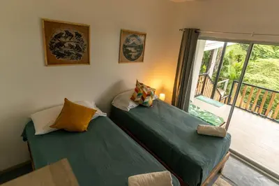 two twin beds in a room with a window at Casa MONO in Santa Teresa Beach