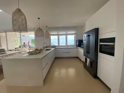 a kitchen with white cabinets and a black refrigerator at CASA AYLA A - stunning 5BR Ocean view house & infinity pool in Flamingo in Playa Flamingo