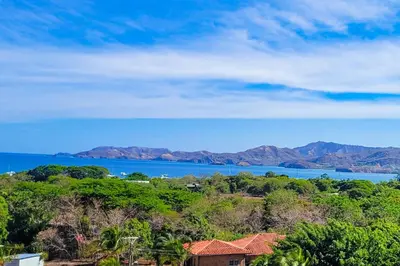 a house on a hill with a view of the water at Casa Nalifos in Playa Flamingo