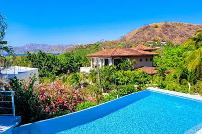 a villa with a swimming pool and a mountain at Casa Nalifos in Playa Flamingo