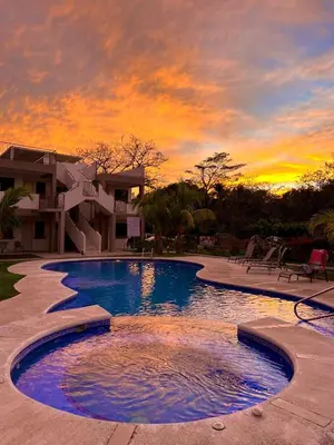 a large swimming pool with a sunset in the background at Coco Boho Beach Condo in Coco
