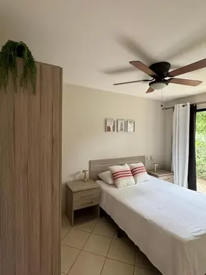 a bedroom with a bed with a ceiling fan at Coco Boho Beach Condo in Coco