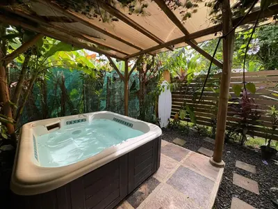 a hot tub under a pergola in a garden at Colibrí Villa, 800 m from Beach in Uvita