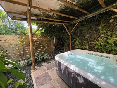 a hot tub under a pergola in a garden at Colibrí Villa, 800 m from Beach in Uvita