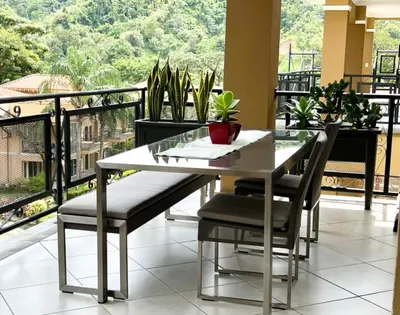 a table and chairs on a balcony with plants at Spacious Penthouse with pool & Jungle Views in La Mona