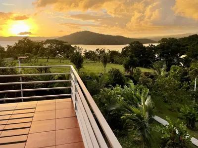 a balcony with a view of the ocean at sunset at The Fruit Tree Garden Bromeliad Suite in Nuevo Arenal