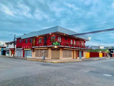 a red building on the side of a street at Hotel Costa del Sol in Puerto Limón