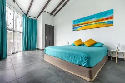 a bedroom with a bed with a painting on the wall at La Casona Eco-Lodge Tortuguero in Tortuguero