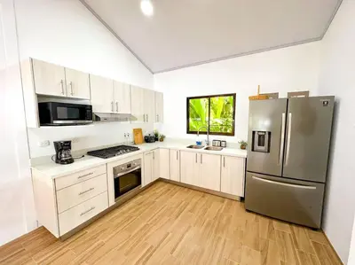 a kitchen with white cabinets and a stainless steel refrigerator at Casa Garza, con a/c y wifi in Quepos