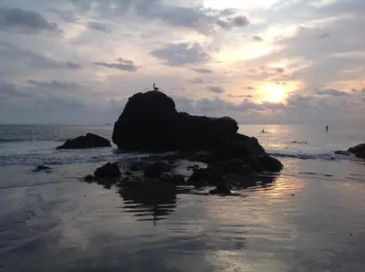 a person standing on a rock on the beach at Kiskadee Casa in Quepos