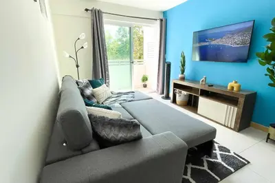 a living room with a couch and a tv at Luxury NEW Apt -24/7 sec- 10 min from SJO Airport in Heredia