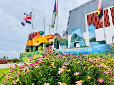 a field of flowers in front of a large sign at Hostal Nuevo Arenal downtown, private rooms with bathroom in Nuevo Arenal