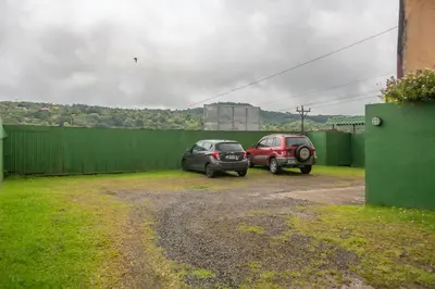 two cars parked in a parking lot next to a fence at Hostal Nuevo Arenal downtown, private rooms with bathroom in Nuevo Arenal