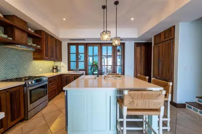 a kitchen with wooden cabinets and a island with a counter top at Casa De Los Sueños- 5 Bedroom Home At Las Catalinas in Playa Danta