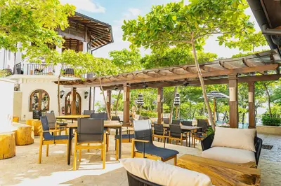 an outdoor patio with tables and chairs and trees at Casa De Los Sueños- 5 Bedroom Home At Las Catalinas in Playa Danta