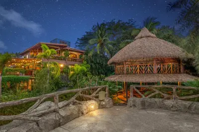 a resort with a large building with a thatch roof at Balu Retreat Center in Playa Junquillal