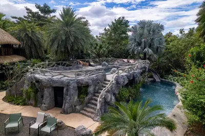 a swimming pool in a garden with a waterfall at Balu Retreat Center in Playa Junquillal