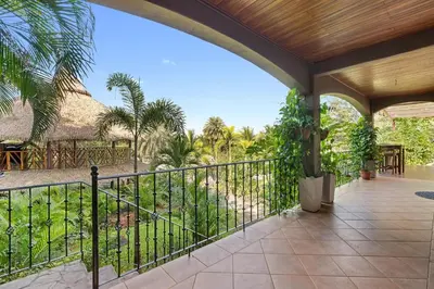 an outdoor patio with a fence and palm trees at Balu Retreat Center in Playa Junquillal