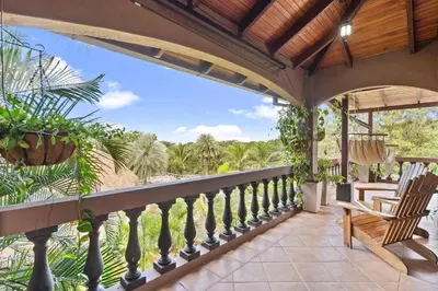 an outdoor balcony with a view of the beach and palm trees at Balu Retreat Center in Playa Junquillal