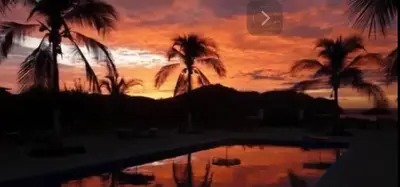 a sunset with palm trees and a swimming pool at Buena Vista Coco in Coco
