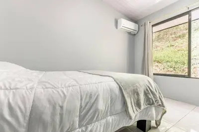a white bedroom with a bed and a window at Villas Anna Bertha 2 noches minimo in San Isidro