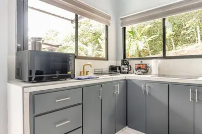 a kitchen with gray cabinets and a microwave at Villas Anna Bertha 2 noches minimo in San Isidro