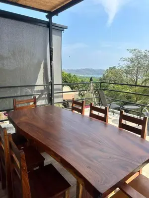 a wooden table on a balcony with chairs around it at Sunset Villa - Upper Poolside in Sámara