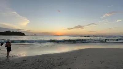 a group of people standing on the beach at sunset at Sunset Villa - Upper Poolside in Sámara