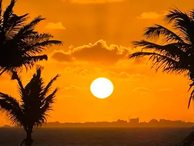 an orange sunset over the ocean with palm trees at Sunset Villa - Upper Poolside in Sámara