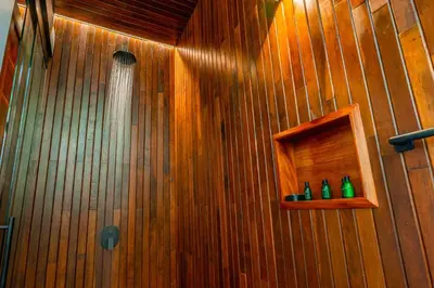a shower with three green bottles on a wooden wall at Villa Morpho - Luxury Jungle House at Ecolirios Green Community in Guácimo