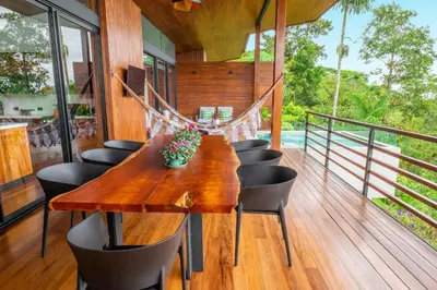 a wooden table and chairs on a deck at Villa Morpho - Luxury Jungle House at Ecolirios Green Community in Guácimo