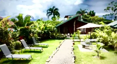 a garden with chairs and tables and a house at Cabañas Litos #3 in Fortuna