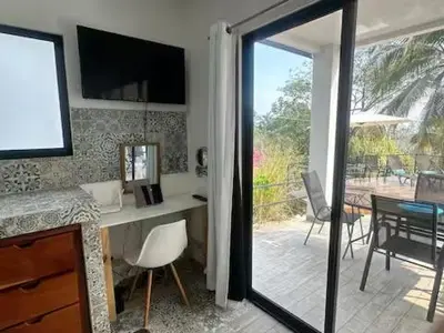 a room with a desk and a balcony with a table and chairs at Sunset Villa - Stunning Poolside in Sámara