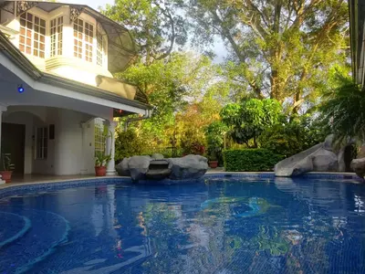 a swimming pool in a yard with a house at Alameda Cariari Boutique Hotel in San José
