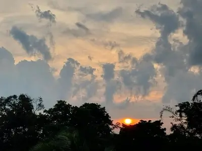 a sunset with clouds and trees in the foreground at Arenal Vistas del Paraiso in Nuevo Arenal