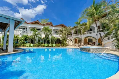 a swimming pool in front of a building with palm trees at Hotel Mar Rey in Tamarindo