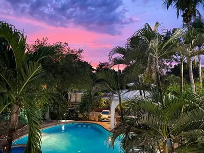 a pool with palm trees in front of a sunset at Hotel Mar Rey in Tamarindo