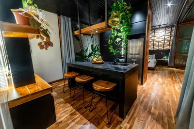 a kitchen with a black island with stools and plants at Danta Santa Lofts in Fortuna