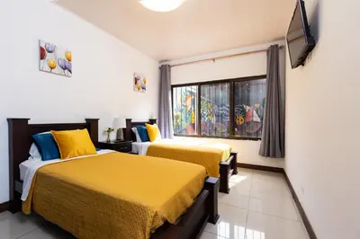 two beds in a room with a window at Viva Guest House in San José