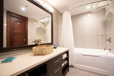 a bathroom with a sink and a tub and a mirror at Crocs Resort & Casino in Jacó