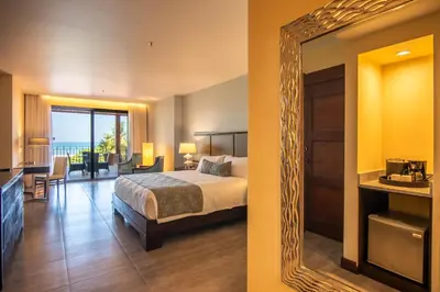 a hotel room with a bed and a mirror at Crocs Resort & Casino in Jacó