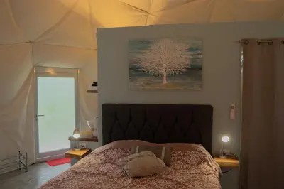 a bedroom with a bed with a tree on the wall at Pura Vista Glamping in El Castillo de La Fortuna