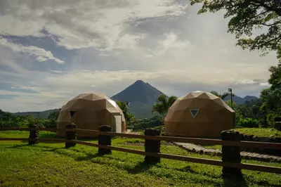 two tents in a field next to a fence at Pura Vista Glamping in El Castillo de La Fortuna