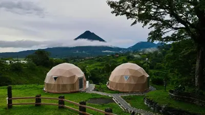 a couple of tents with a mountain in the background at Pura Vista Glamping in El Castillo de La Fortuna