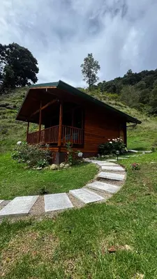 a log cabin with a porch on a hill at Entre Árboles Lodge in San Gerardo de Dota