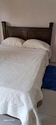 a bed with white sheets and a wooden head board at Paradise Rio Celeste 2 in Bijagua