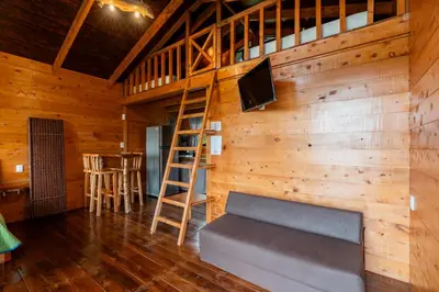 a room with a couch and a tv and a ladder at Cabaña El Ciprés: Vistas increíbles y Mirador in Turrialba