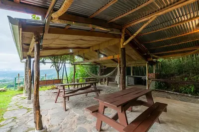 a wooden pavilion with benches and a hammock at Cabaña El Ciprés: Vistas increíbles y Mirador in Turrialba