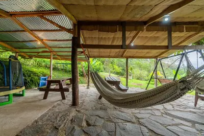 a hammock in a pavilion with a table and a bench at Cabaña El Ciprés: Vistas increíbles y Mirador in Turrialba