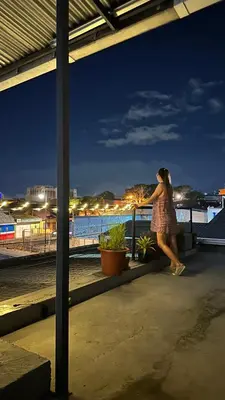 a woman standing on a balcony looking at the beach at night at SJO Oasis Hostel in San José
